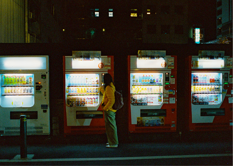 Woman choosing from illuminated vending machines